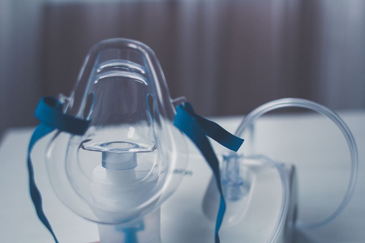 Clear oxygen mask with blue straps and attached tubing